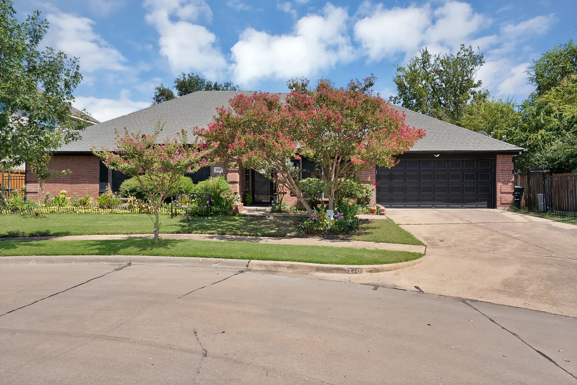 Brick exterior with a gray shingle roof, integrated garage, and a concrete driveway