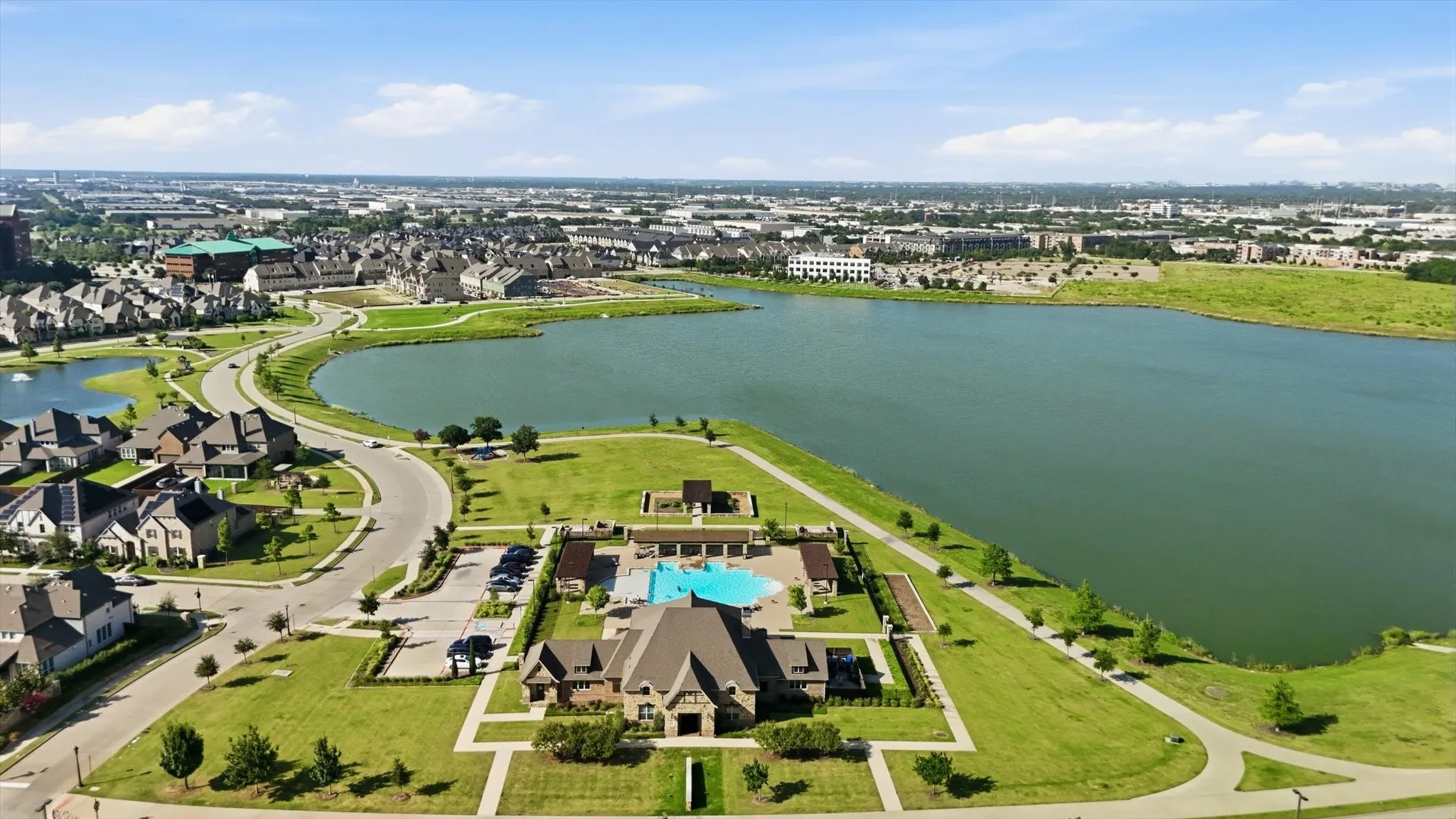 Aerial perspective showcasing the expansive community with a large lake and multiple swimming pools, playgrounds and