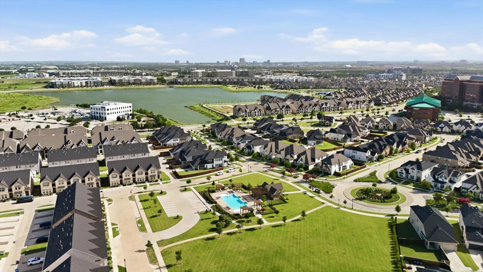 Aerial perspective showcasing the community with a large lake and multiple swimming pools, playgrounds and