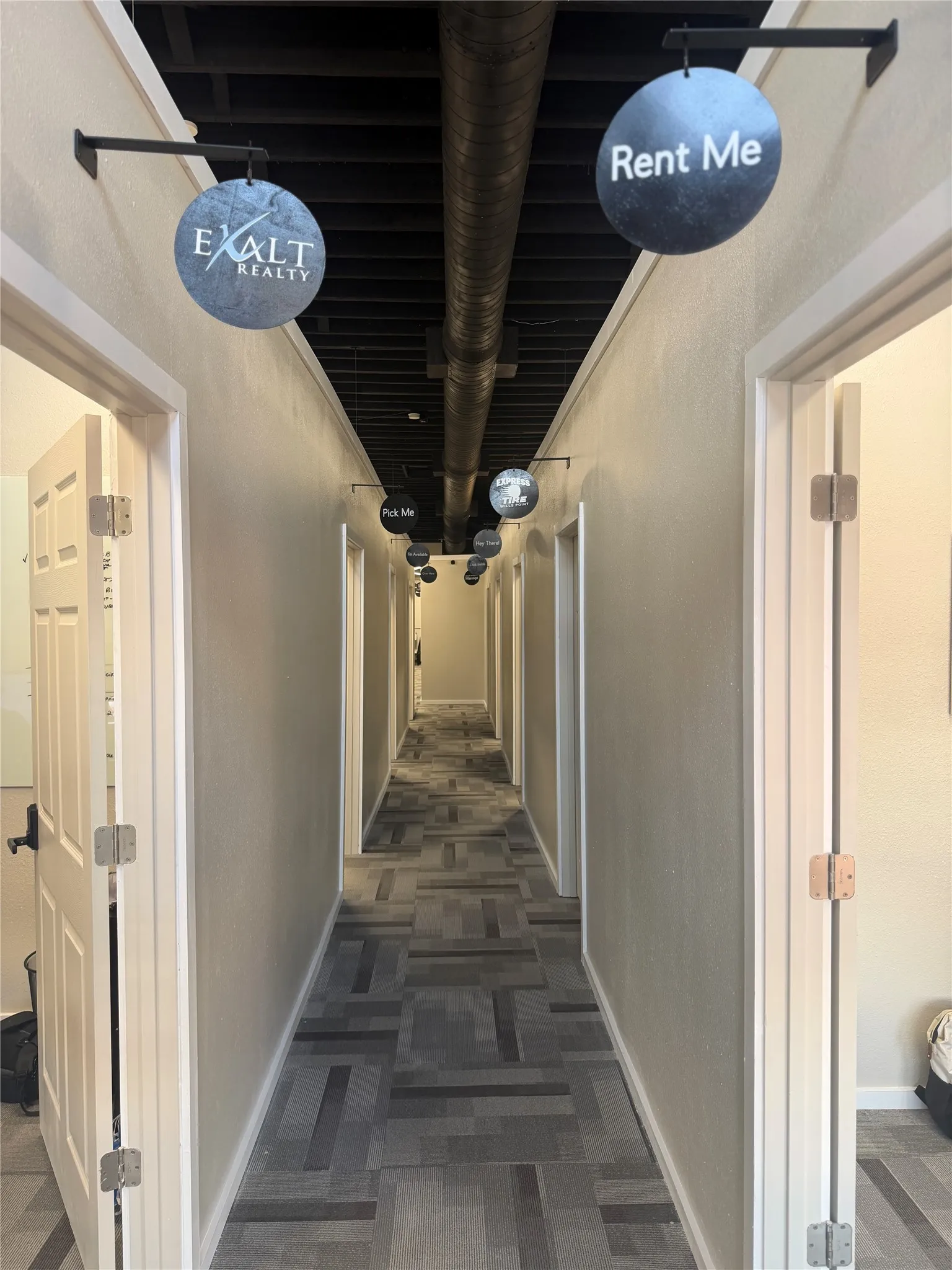 Hallway with patterned flooring, exposed ceiling ductwork, and overhead lighting