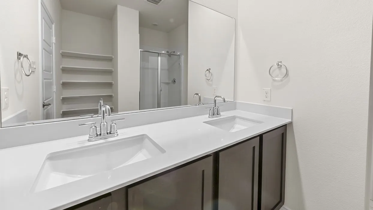 Dual vanity with integrated sinks, chrome fixtures, dark wood-finish cabinetry, and a large mirror
