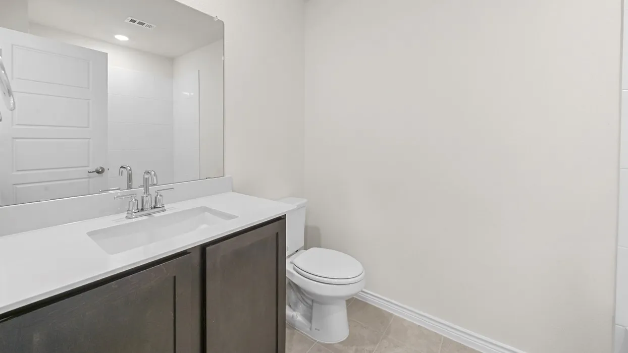 Built-in vanity with dark wood-finish cabinetry, integrated sink, and chrome faucet