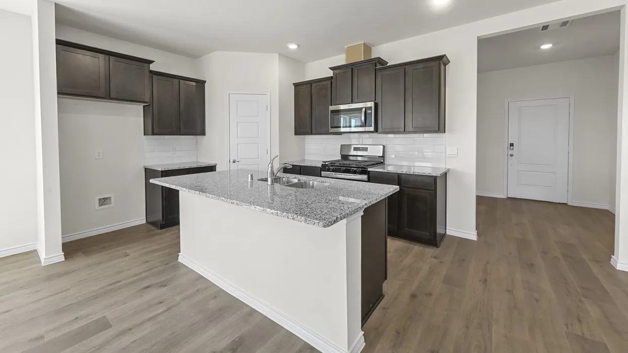 Kitchen featuring wood-finish flooring, dark wood cabinetry, white subway tile backsplash, and a central island with a granite-style countertop