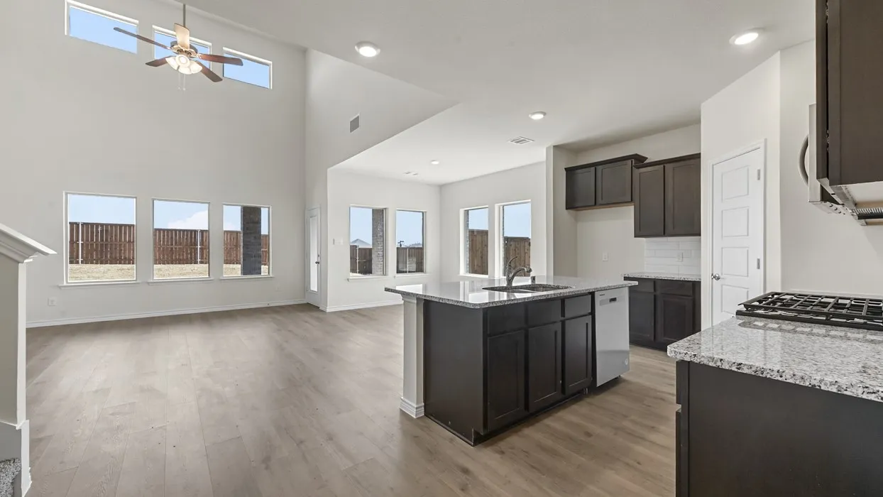 Open-concept living area featuring high ceilings, wood-finish flooring, a kitchen island with a sink, built-in cabinetry, and integrated appliances