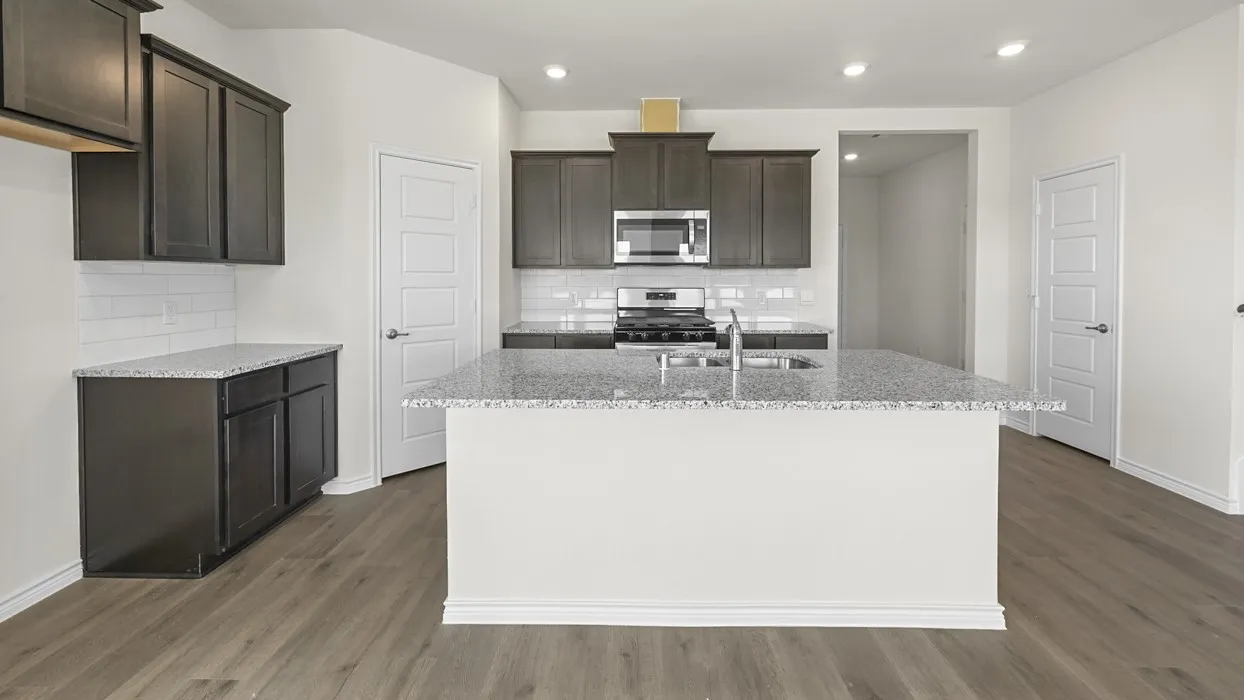 Modern kitchen featuring wood-finish flooring, dark cabinetry, light countertops, a white subway tile backsplash, and stainless steel appliances