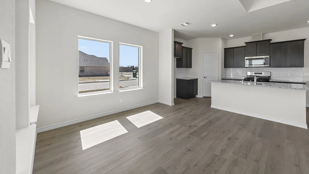 Open-concept living area with wood-finish flooring, two large windows, and recessed lighting