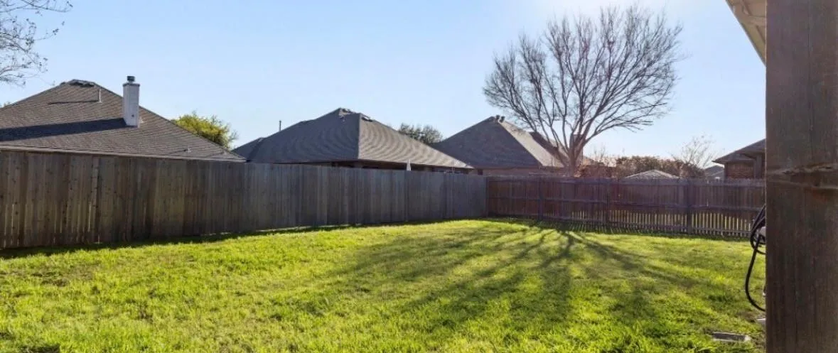 Expansive grassy yard with wood fencing and a mature tree