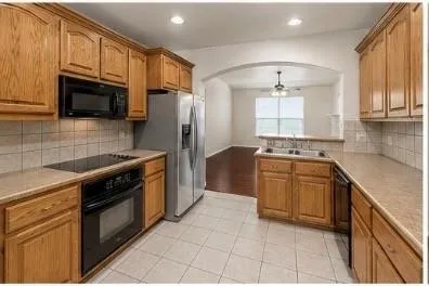 Kitchen featuring wood cabinetry, integrated appliances, tile flooring, and an arched entryway