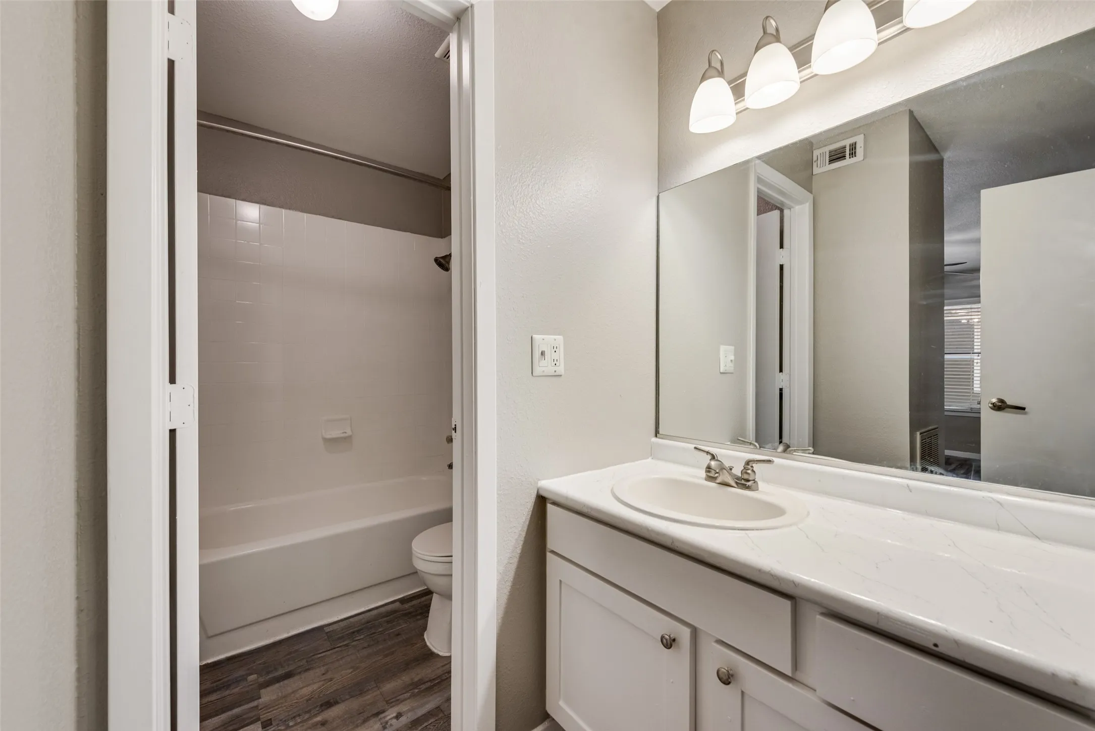 White vanity with a single basin sink, brushed nickel faucet, and a large mirror