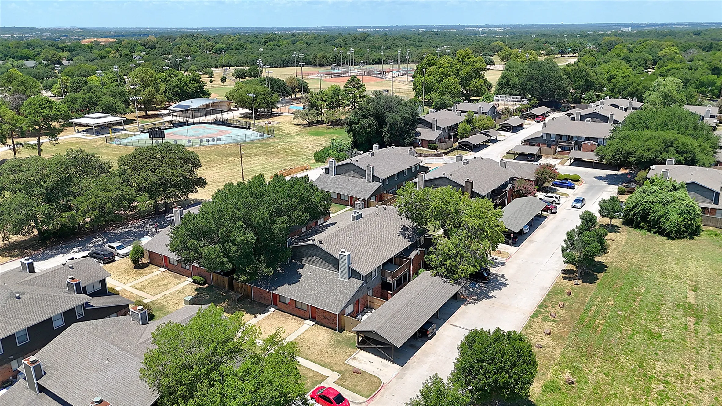 Residential complex with multiple buildings, carports, and mature trees