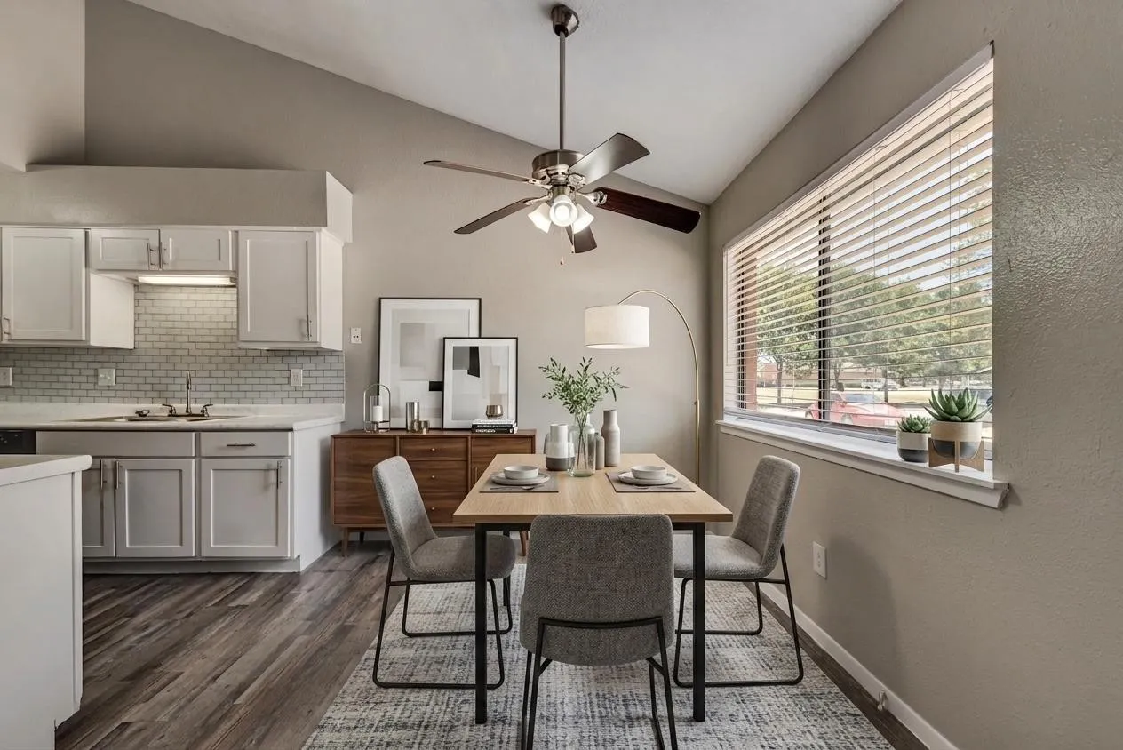 Wood-finish flooring, vaulted ceiling, ceiling fan, white cabinetry with light-colored countertops, and a subway tile backsplash