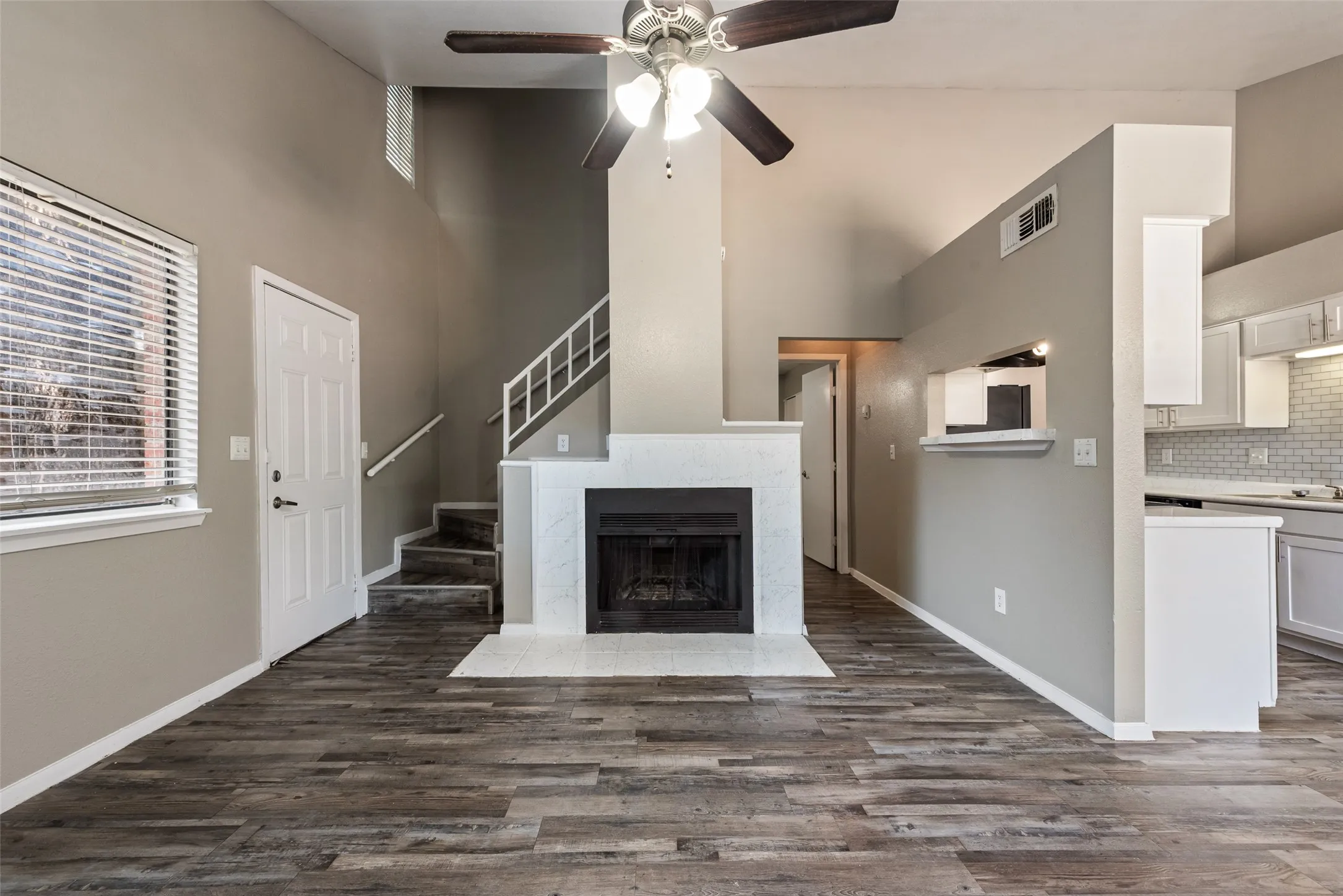 Wood-finish flooring throughout, vaulted ceilings, and a fireplace with a tile surround