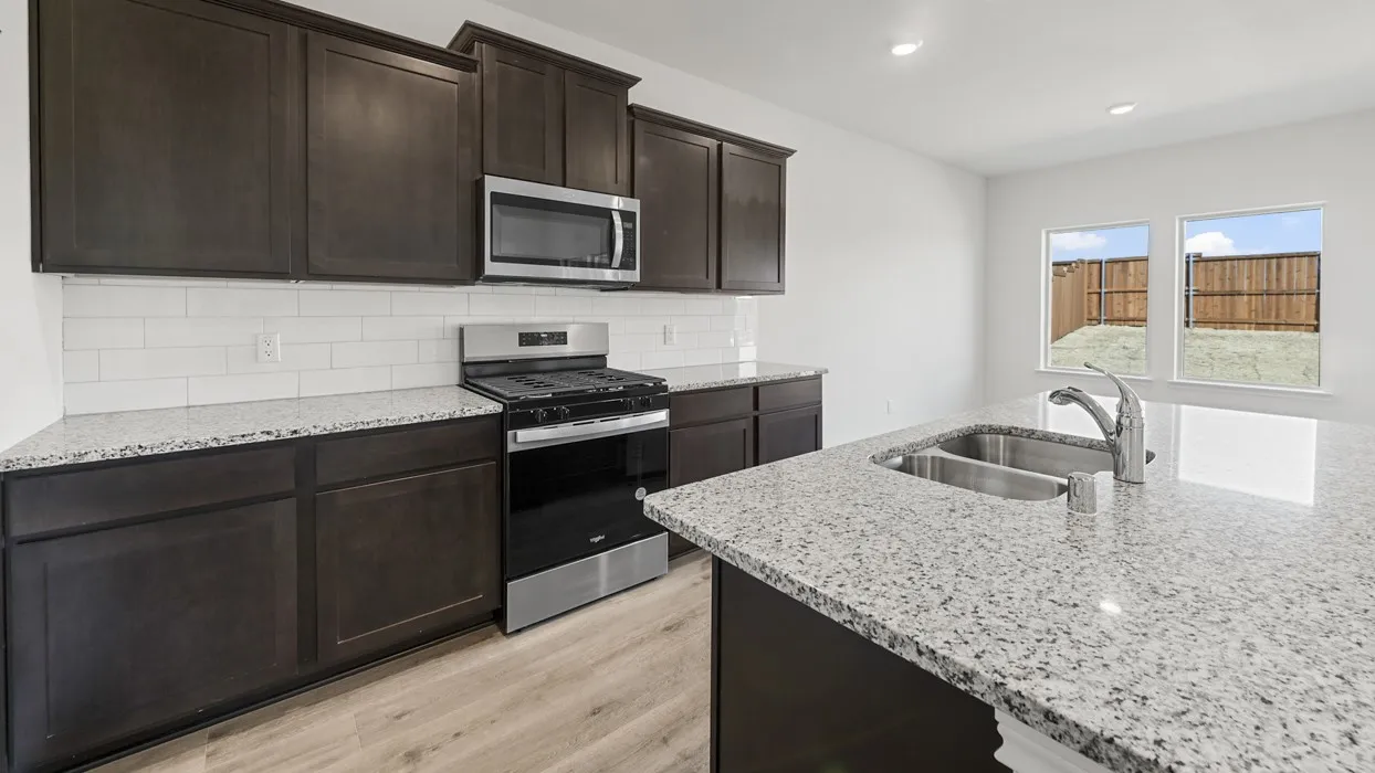 Kitchen featuring dark wood-finish cabinetry, stainless steel appliances, white subway tile backsplash, and light speckled countertops