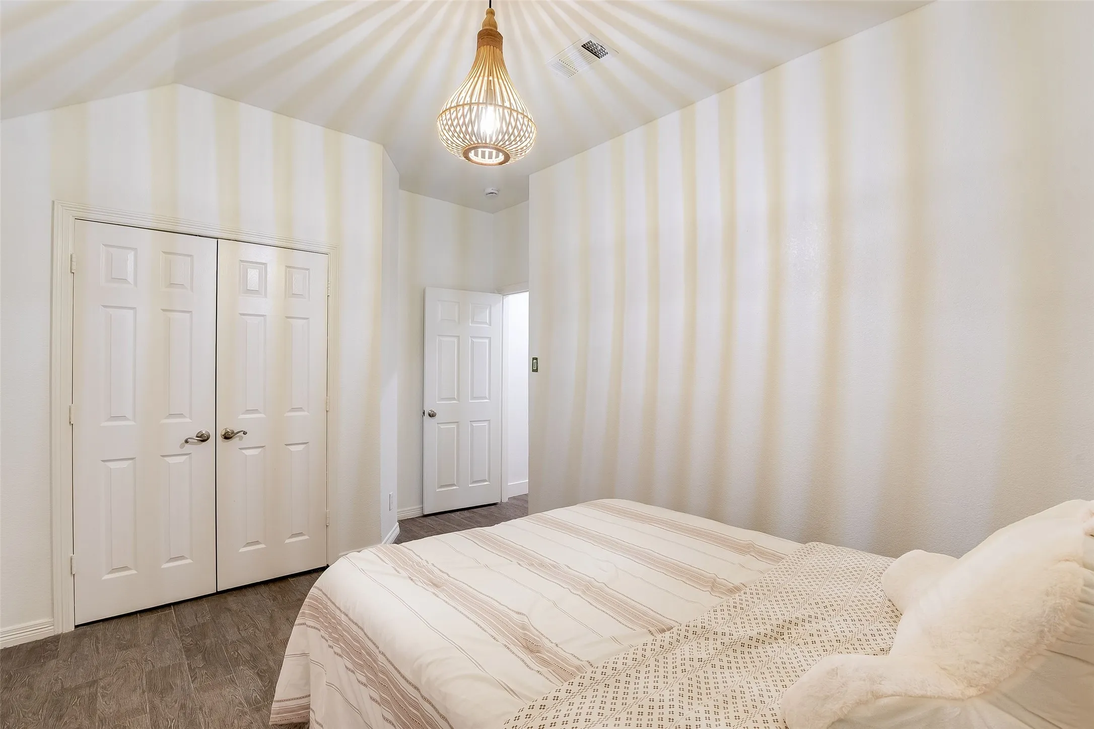Wood-finish flooring, white paneled bifold closet doors, and a decorative pendant light fixture