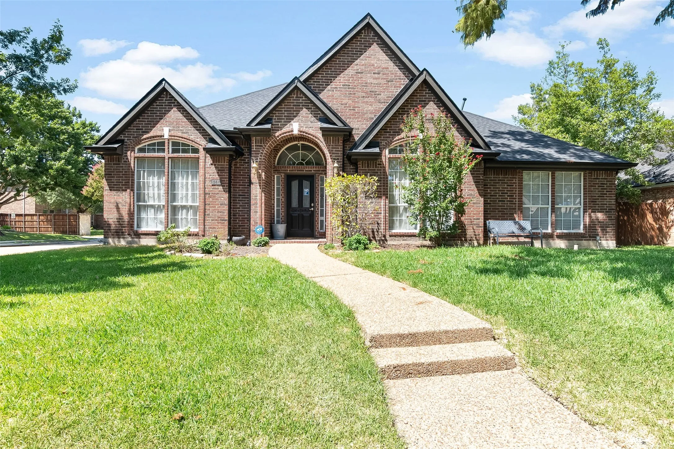 Brick exterior with dark roof shingles, arched entryway, and multiple gables
