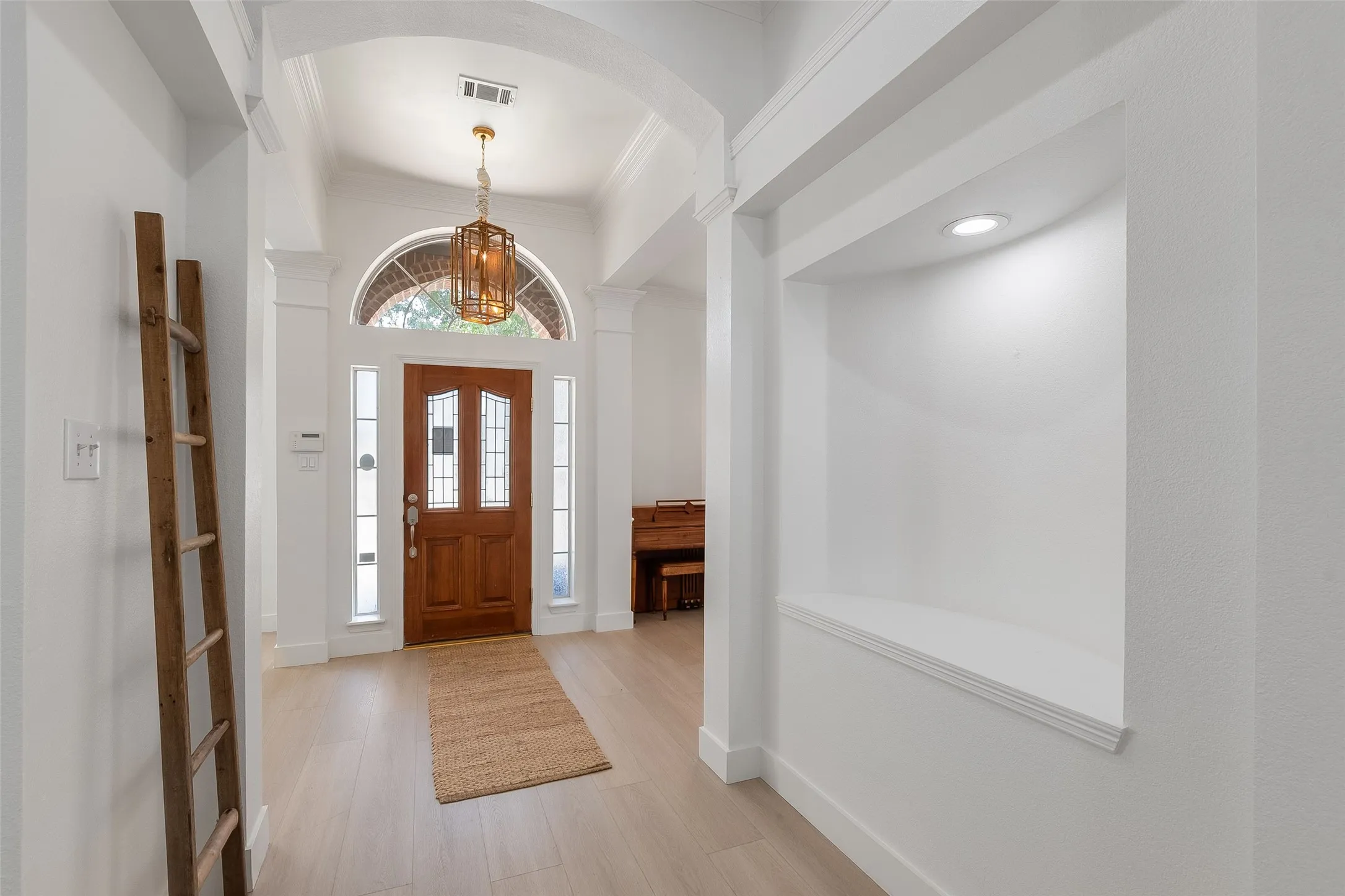 Arched entryway with a wood-panel door, decorative glass inserts, and transom window