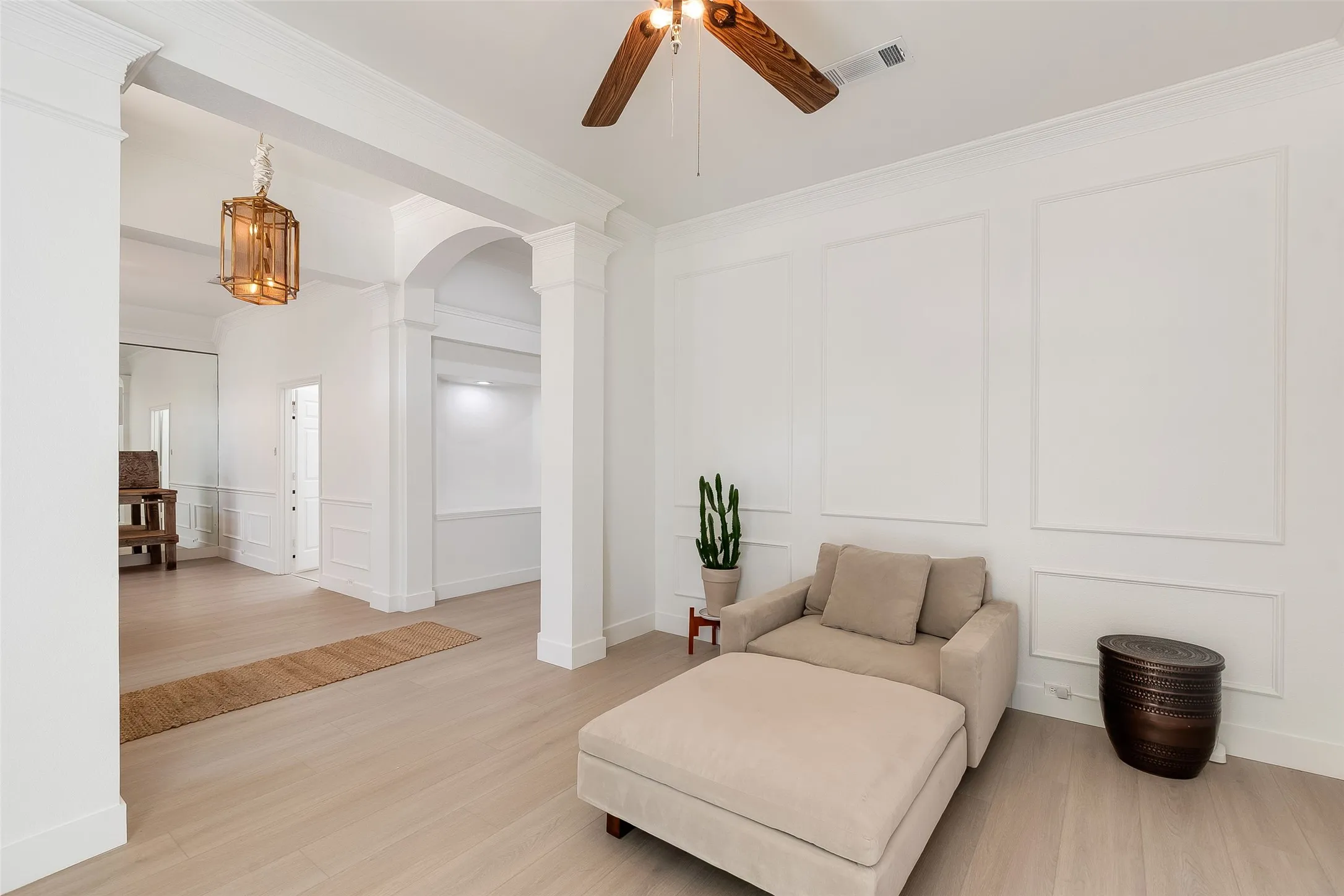 Recessed archway, wood-finish flooring, decorative wall paneling, ceiling fan with wood-finish blades, and a built-in light fixture