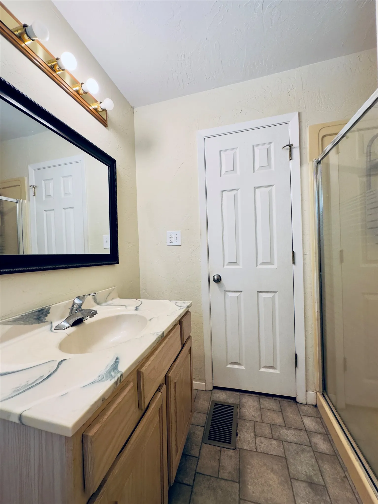 Vanity with an integrated sink, polished chrome faucet, wood-finish cabinetry, and a framed mirror