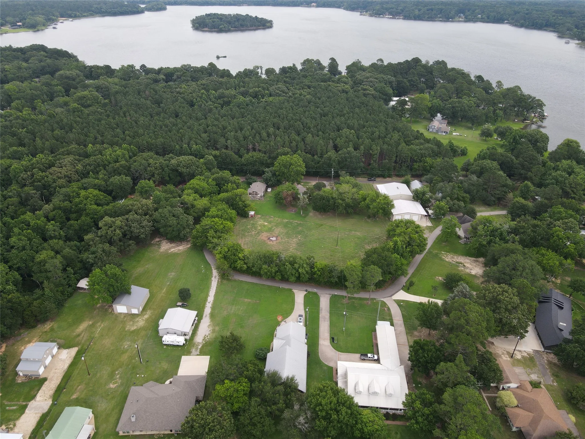 Expansive property featuring a large body of water, wooded perimeter, and open grassy areas