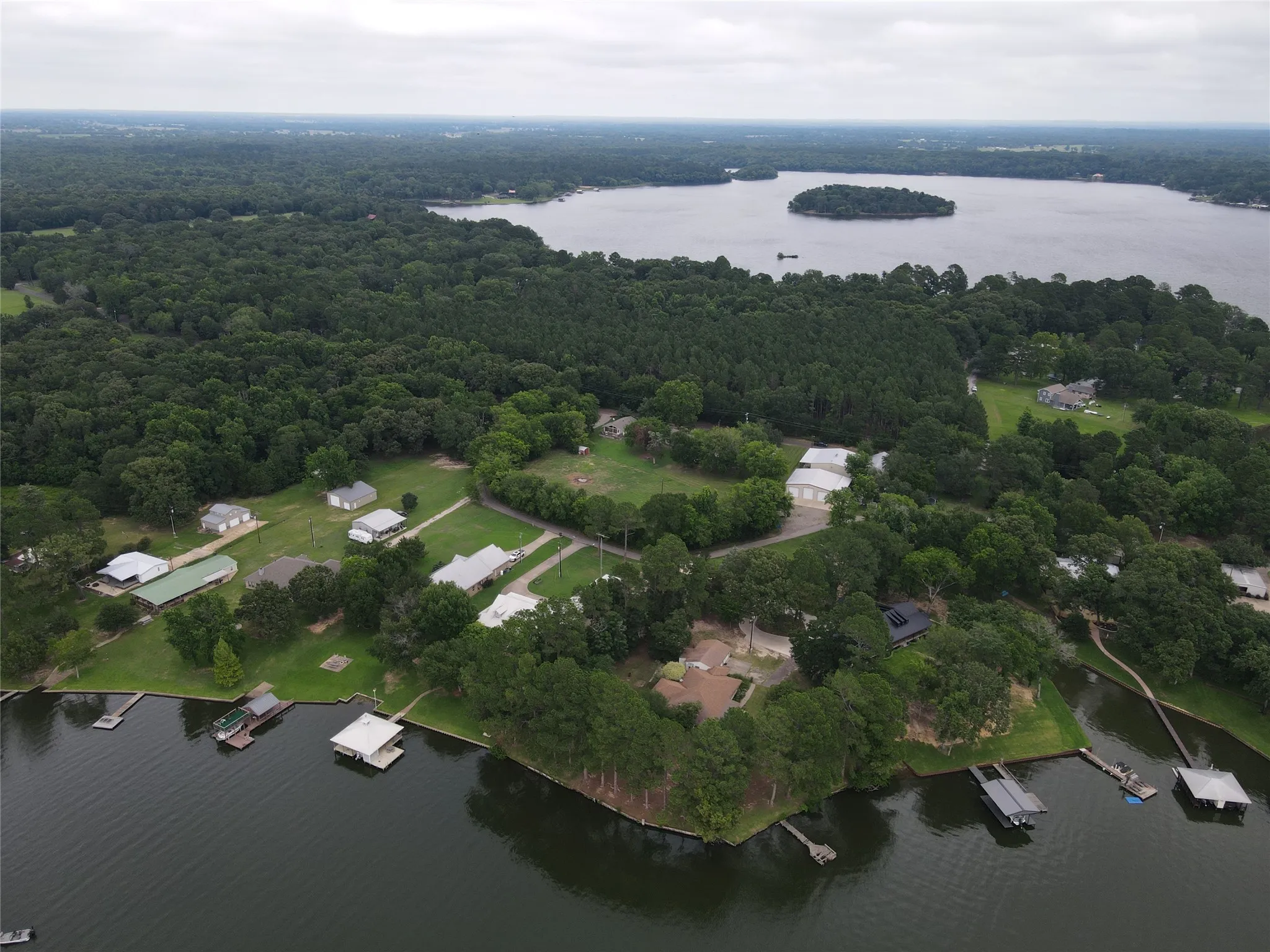 Lake view property with boat ramp, surrounding mature trees, and a distant island