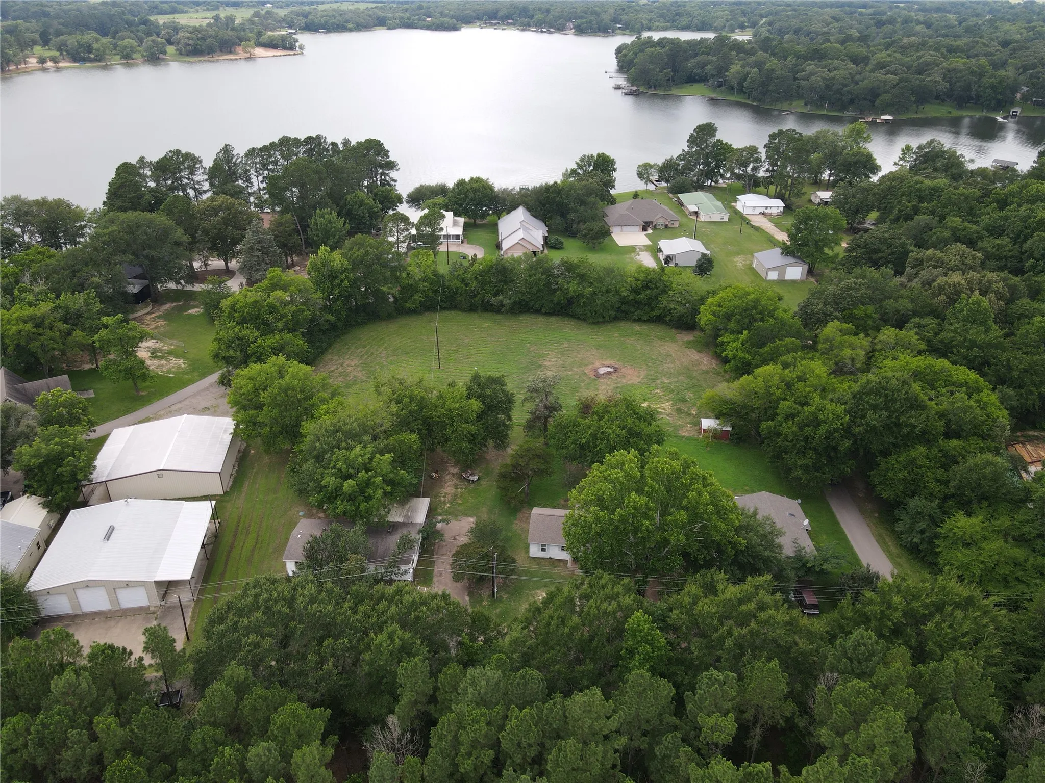 Expansive lakeview property featuring extensive tree coverage and multiple structures