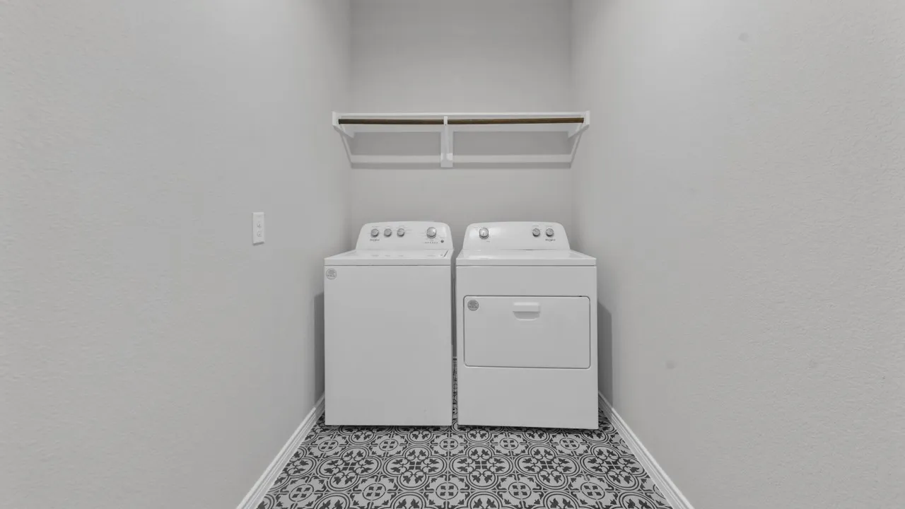 Laundry area featuring patterned floor tile and a wall-mounted shelving unit