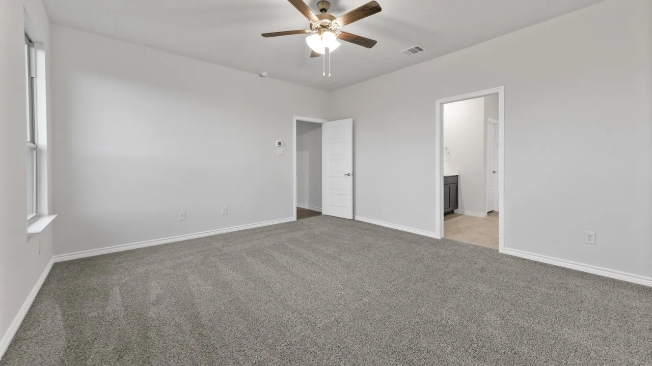 Spacious room featuring vaulted ceilings, gray carpeting, a ceiling fan, and a single window