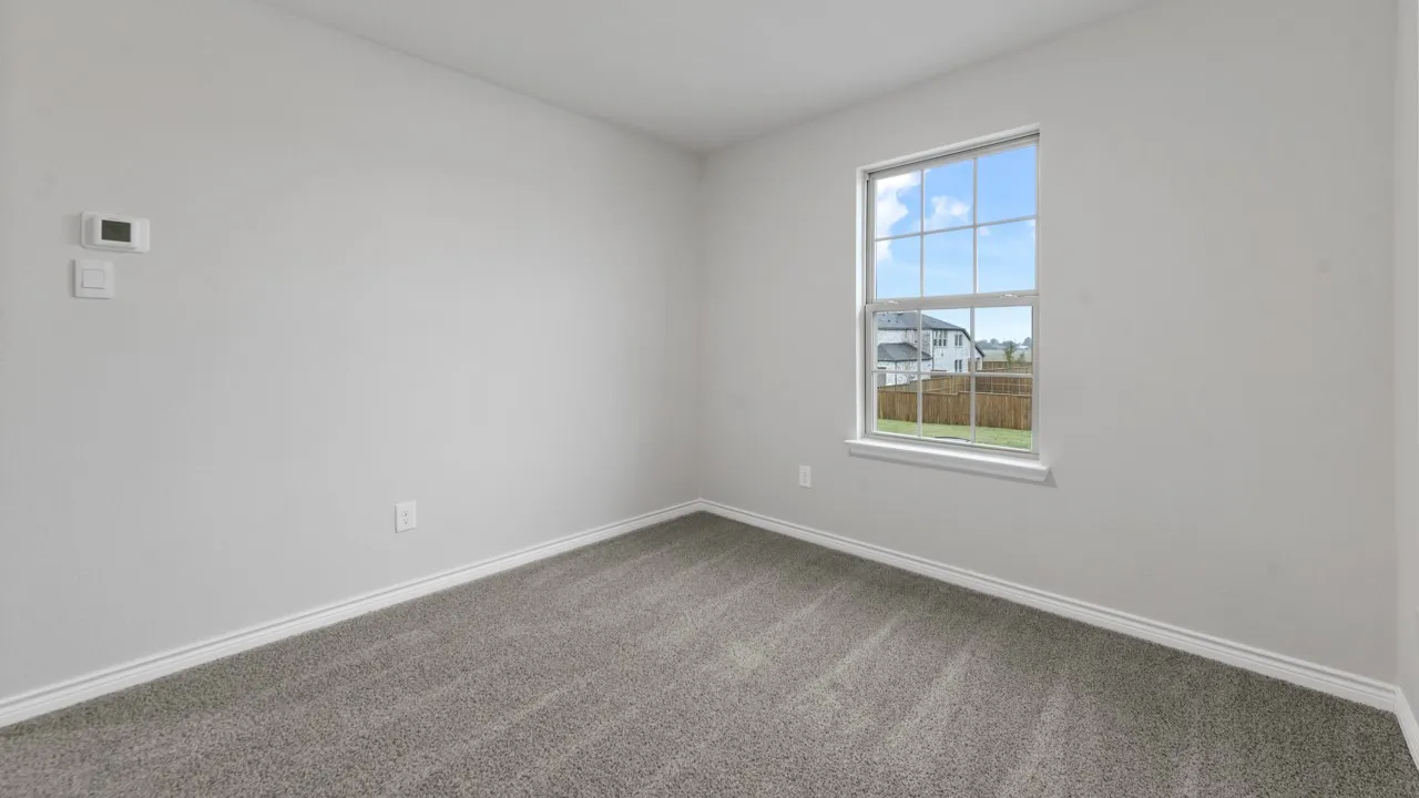 Neutral wall color, carpet flooring, window with white trim, and a digital thermostat