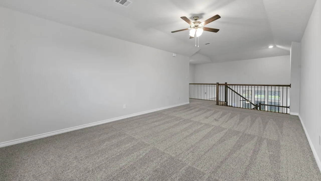 Spacious carpeted area with a ceiling fan, recessed lighting, and a wood and metal baluster railing