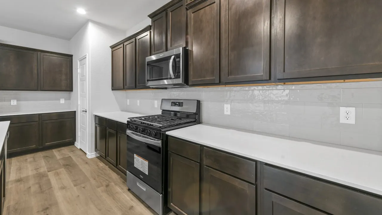 Dark wood-finish cabinetry with stainless steel hardware, white countertops, subway tile backsplash, stainless steel range, and wood-finish flooring