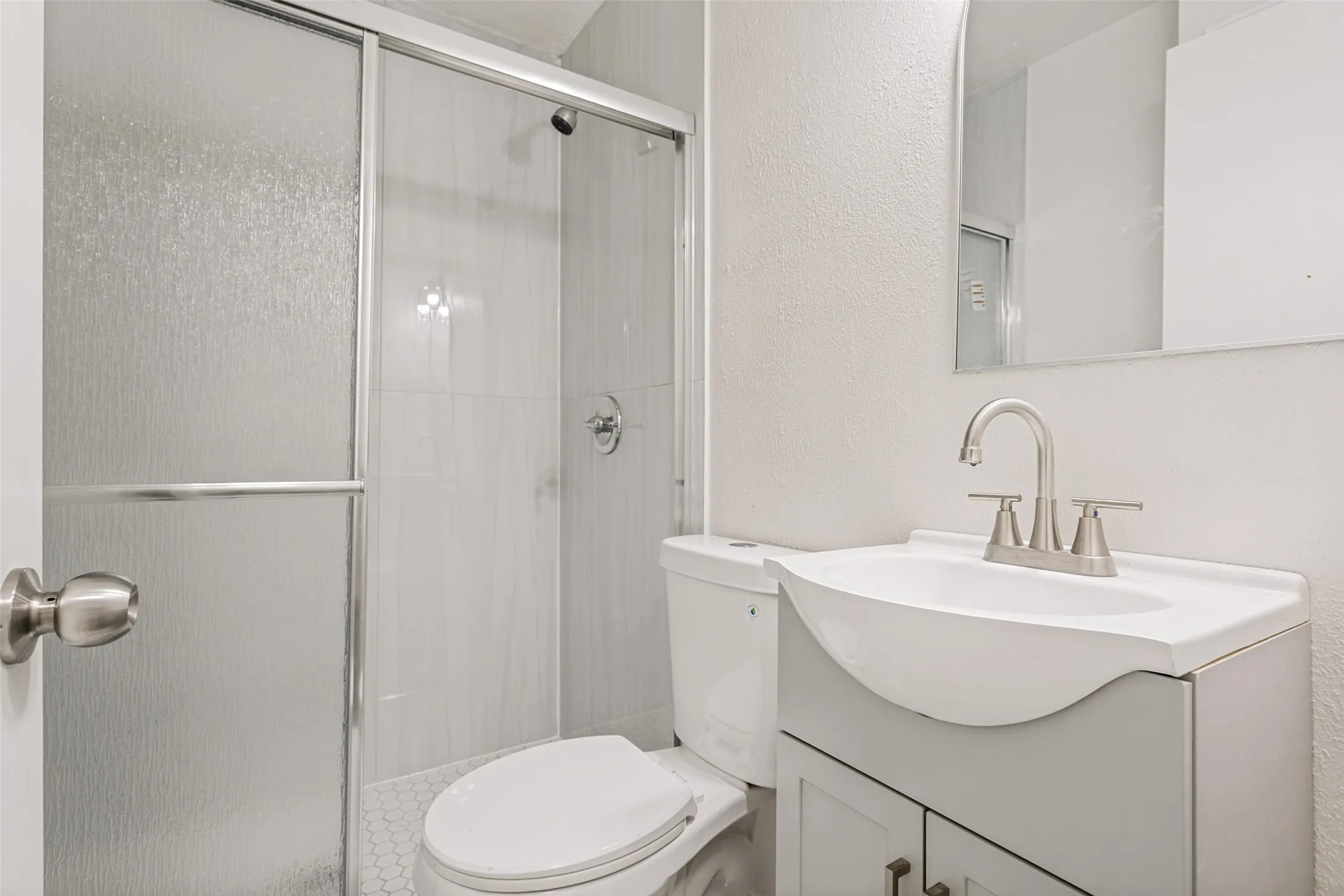 Shower with frosted glass enclosure, white tile surround, and brushed nickel fixtures