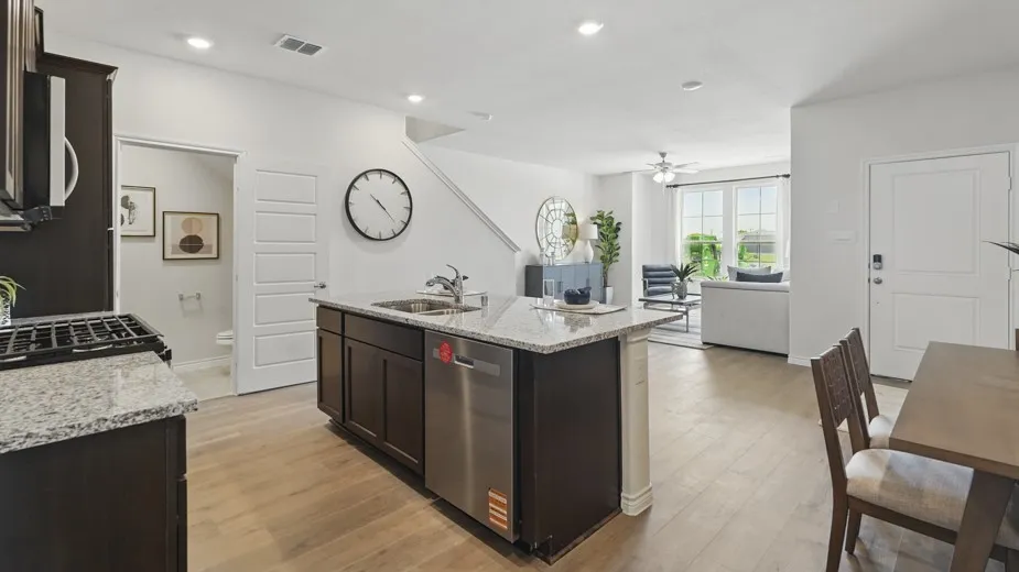 Open-concept living space featuring wood-finish flooring, a kitchen island with stone countertops, stainless steel appliances, and a gas range