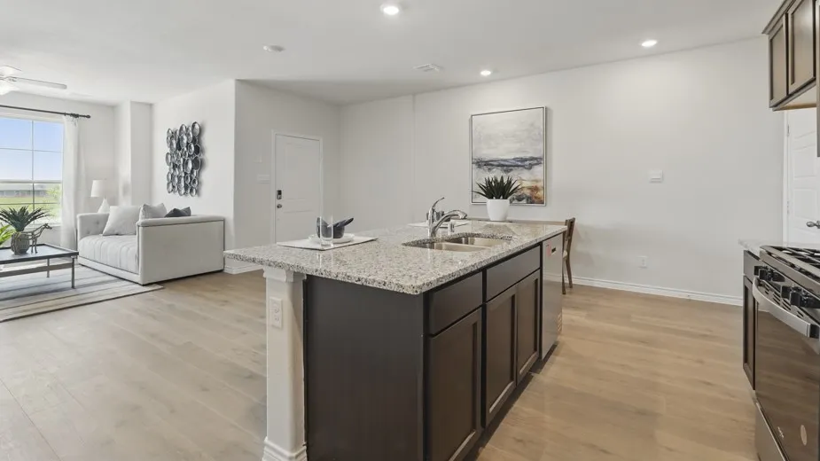 Kitchen island with granite countertops, stainless steel double sink, and dark wood cabinetry