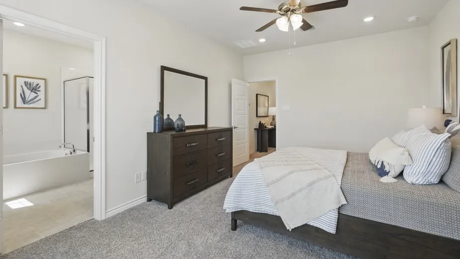 Recessed lighting, ceiling fan, carpeting, and an adjoining bathroom featuring a soaking tub and shower enclosure