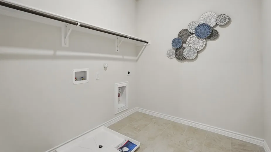 Laundry area with a clothes hanging rod, upper shelf, and tile flooring