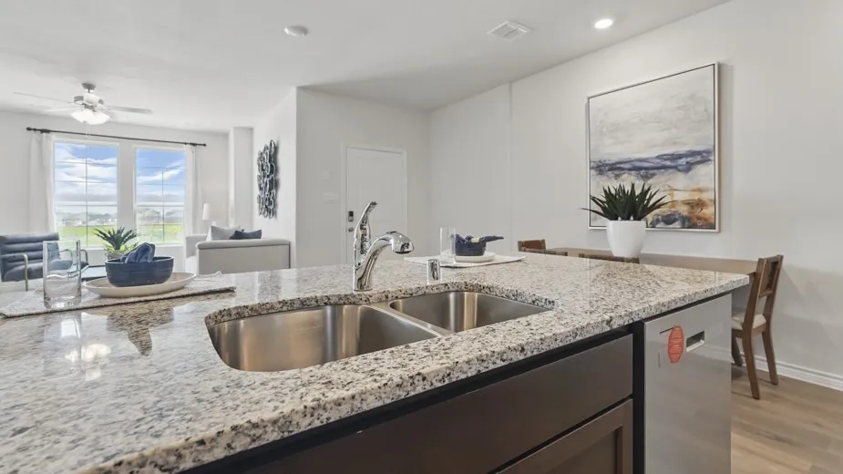 Kitchen island featuring a double basin stainless steel sink, a stainless steel dishwasher, and a light-toned granite countertop