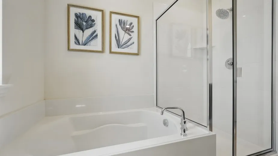 Soaking tub with deck-mounted chrome faucet, glass-enclosed shower with subway tile surround, and chrome rainfall showerhead