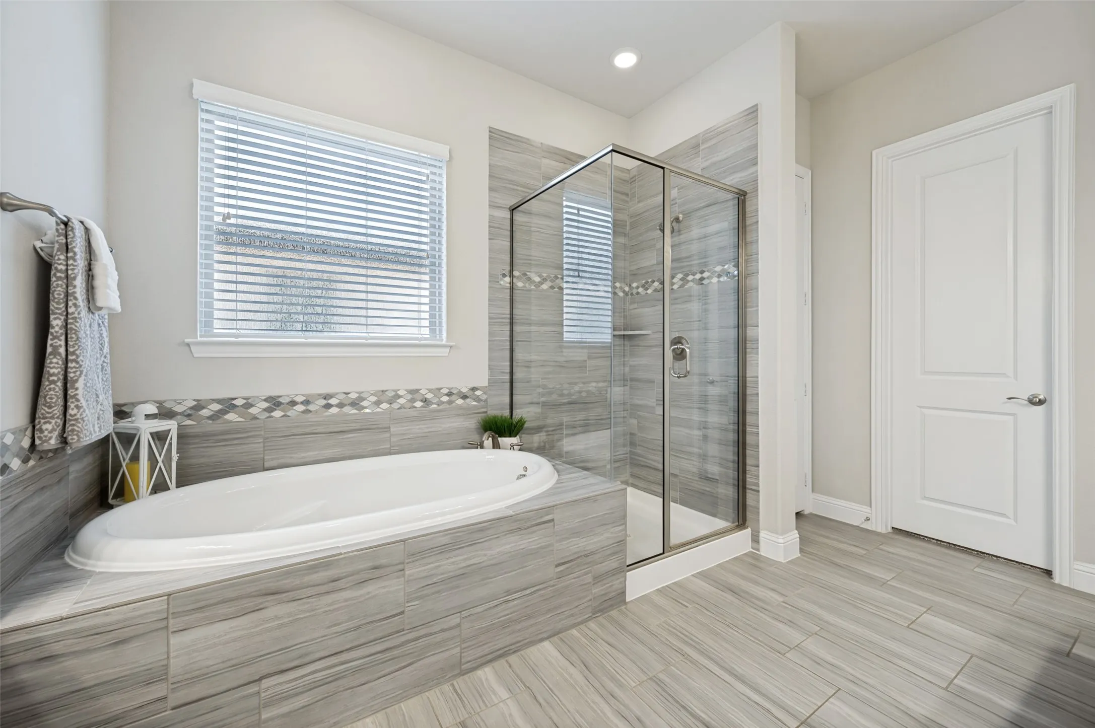Spa-like primary bath featuring a soaking tub, separate glass-enclosed shower, beautiful tilework, and abundant natural light.