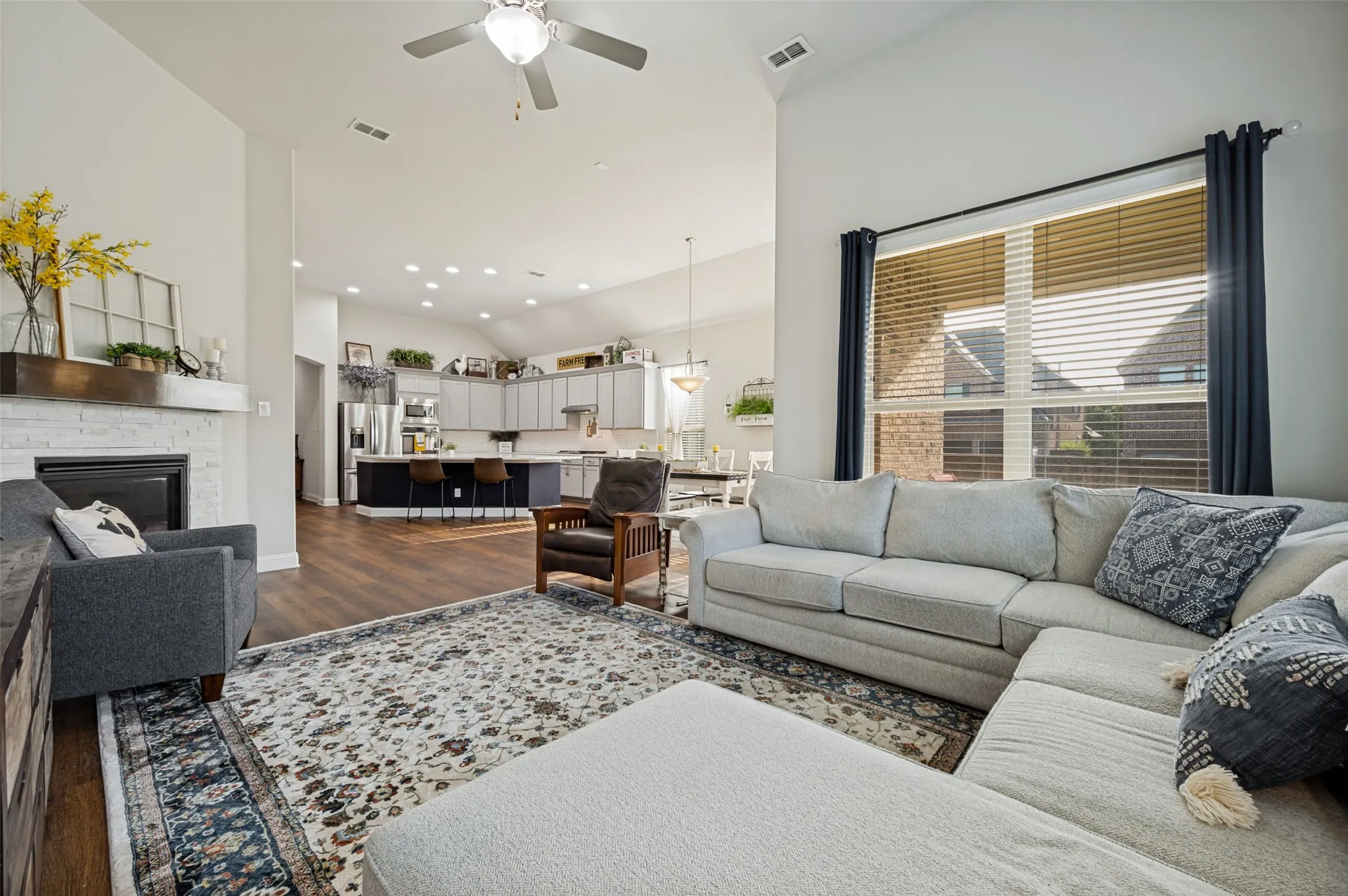 Open-concept living at its best, with vaulted ceilings, beautiful wood flooring, a cozy fireplace, and a seamless flow from the spacious living area into the kitchen and dining space.