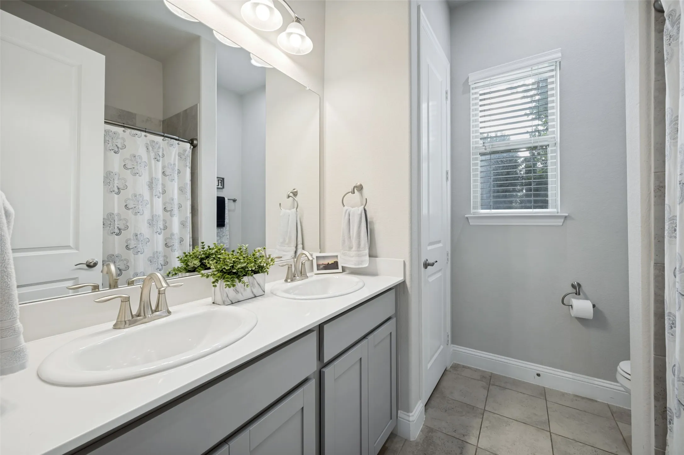 Spacious secondary bathroom featuring a dual-sink vanity, abundant counter space, tub and shower combination, and plenty of natural light.