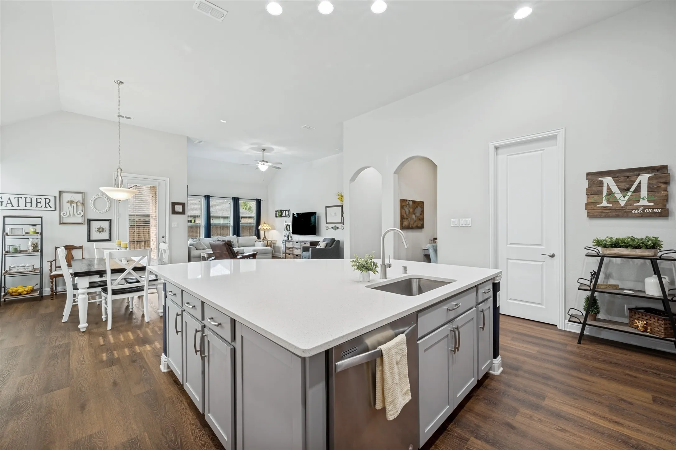 Oversized kitchen island featuring generous prep space, a built-in sink and dishwasher, abundant storage, and an open view into the dining and living areas.