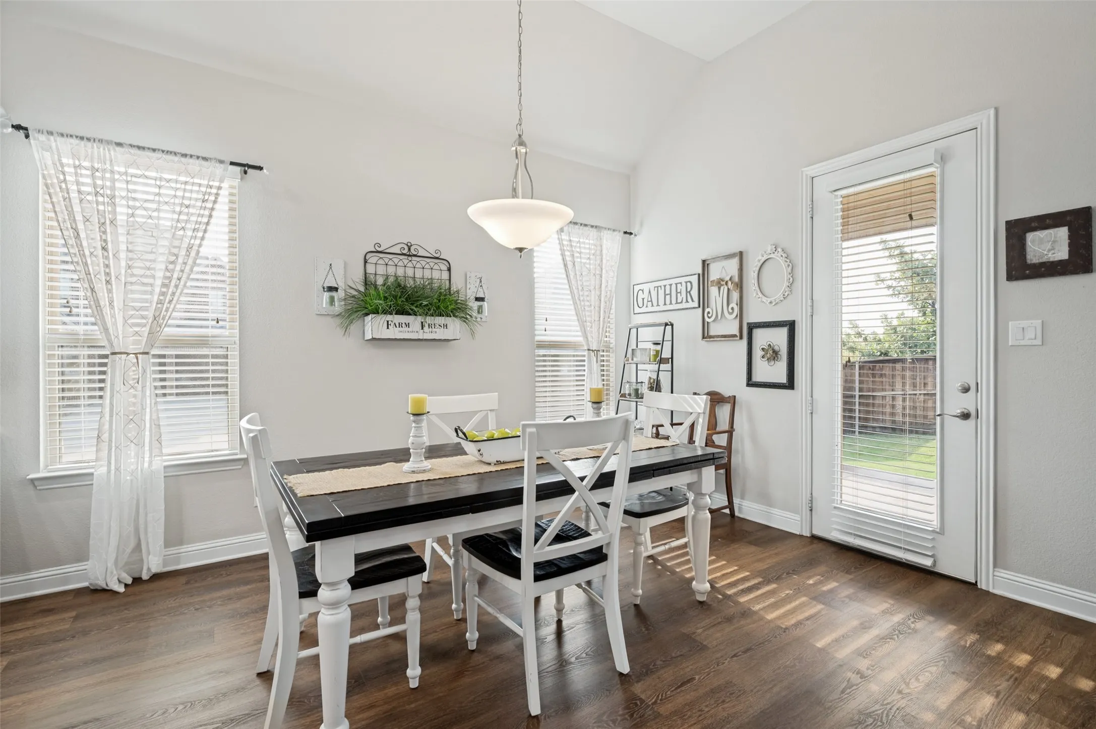 Bright dining area featuring vaulted ceilings, beautiful wood flooring, abundant natural light, and convenient access to the backyard and patio.