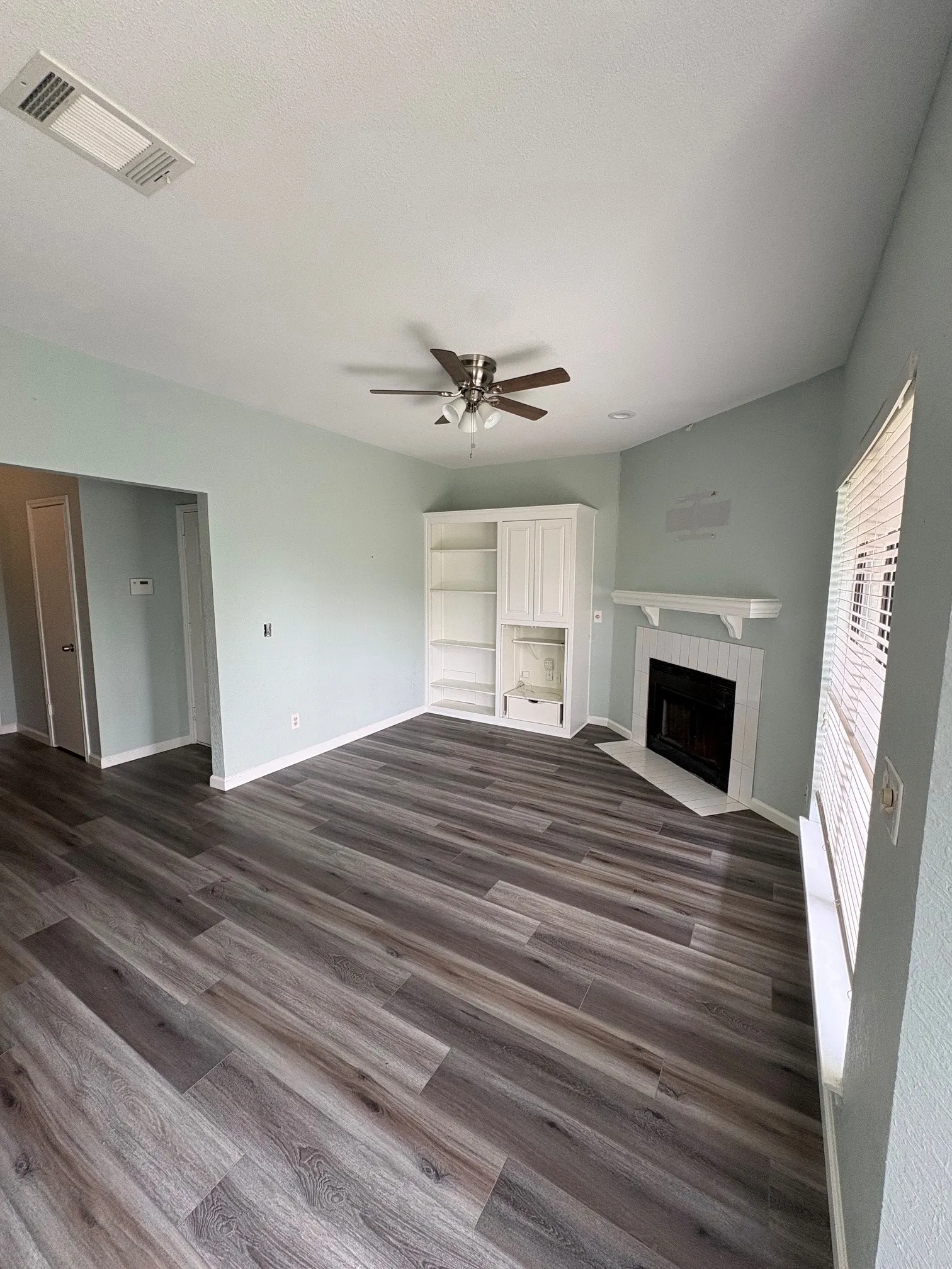 Living room with fireplace, ceiling fan, and built-in cabinet.