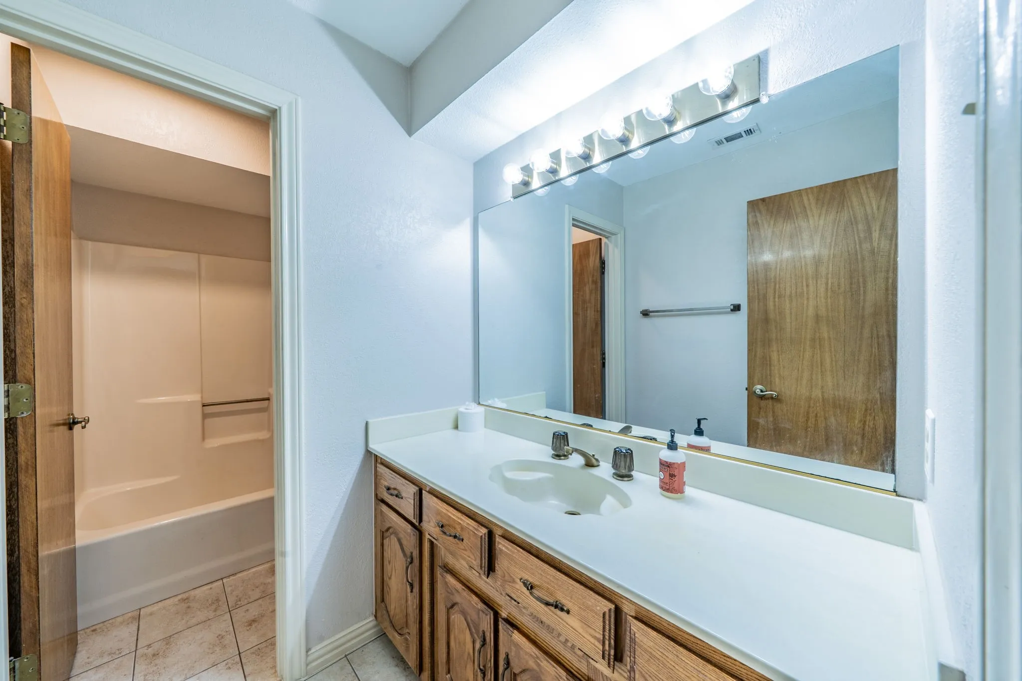 Hall bath has a door separating the tub and toilet from the sink area.
