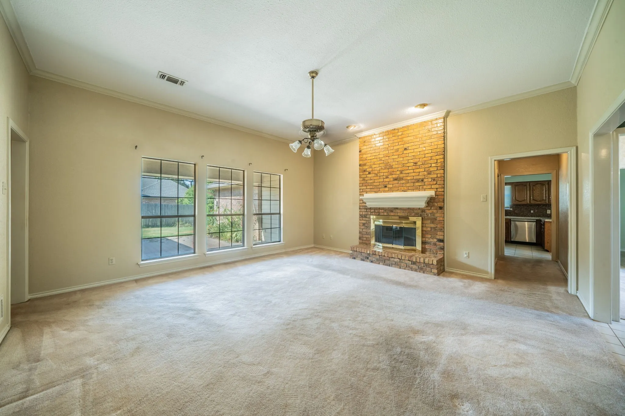 View of family room looking towards the brick fireplace and into the hall to the kitchen.