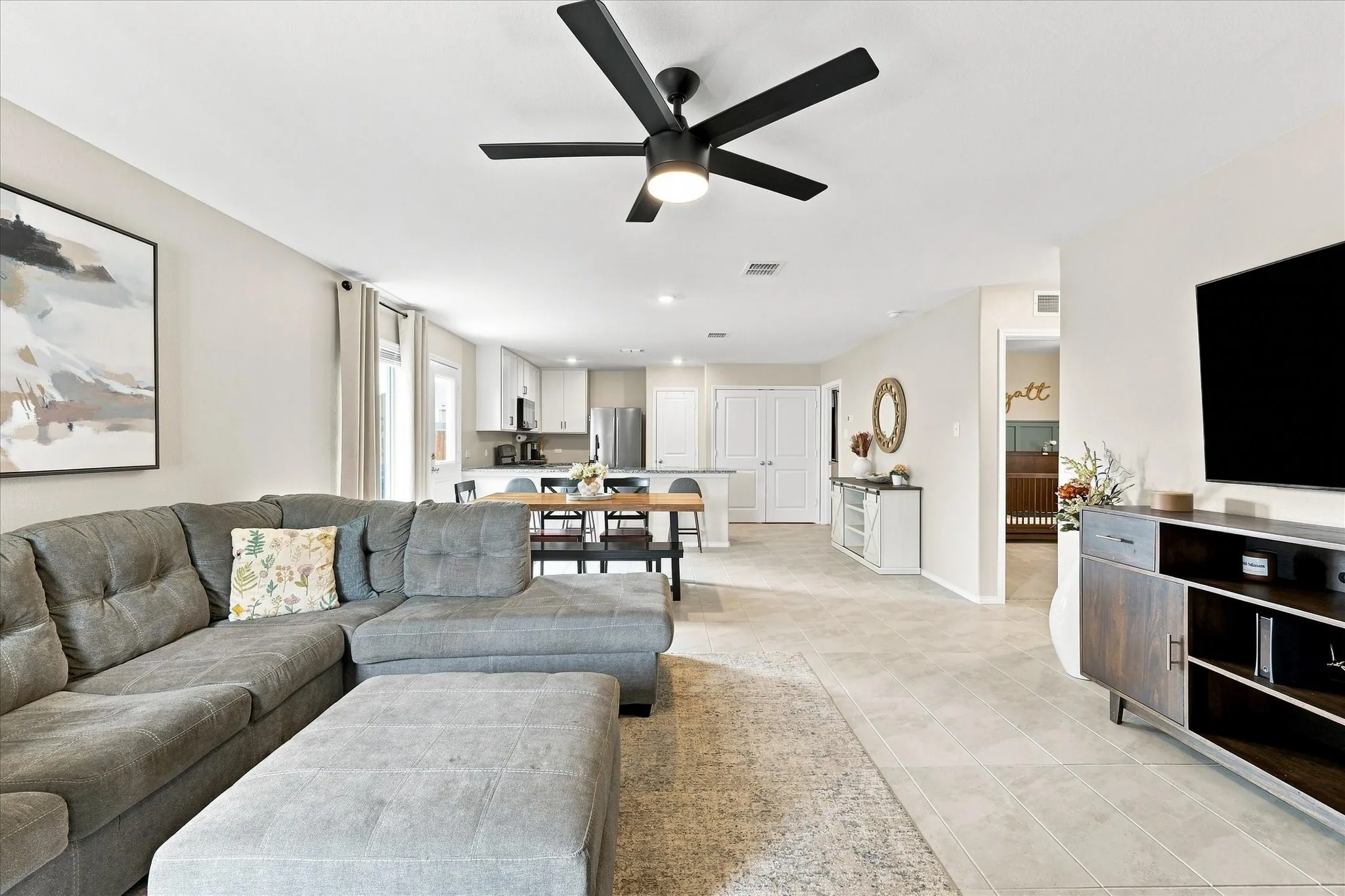 Open-concept living space featuring a modern ceiling fan, tile flooring, recessed lighting, and a kitchen with white cabinetry