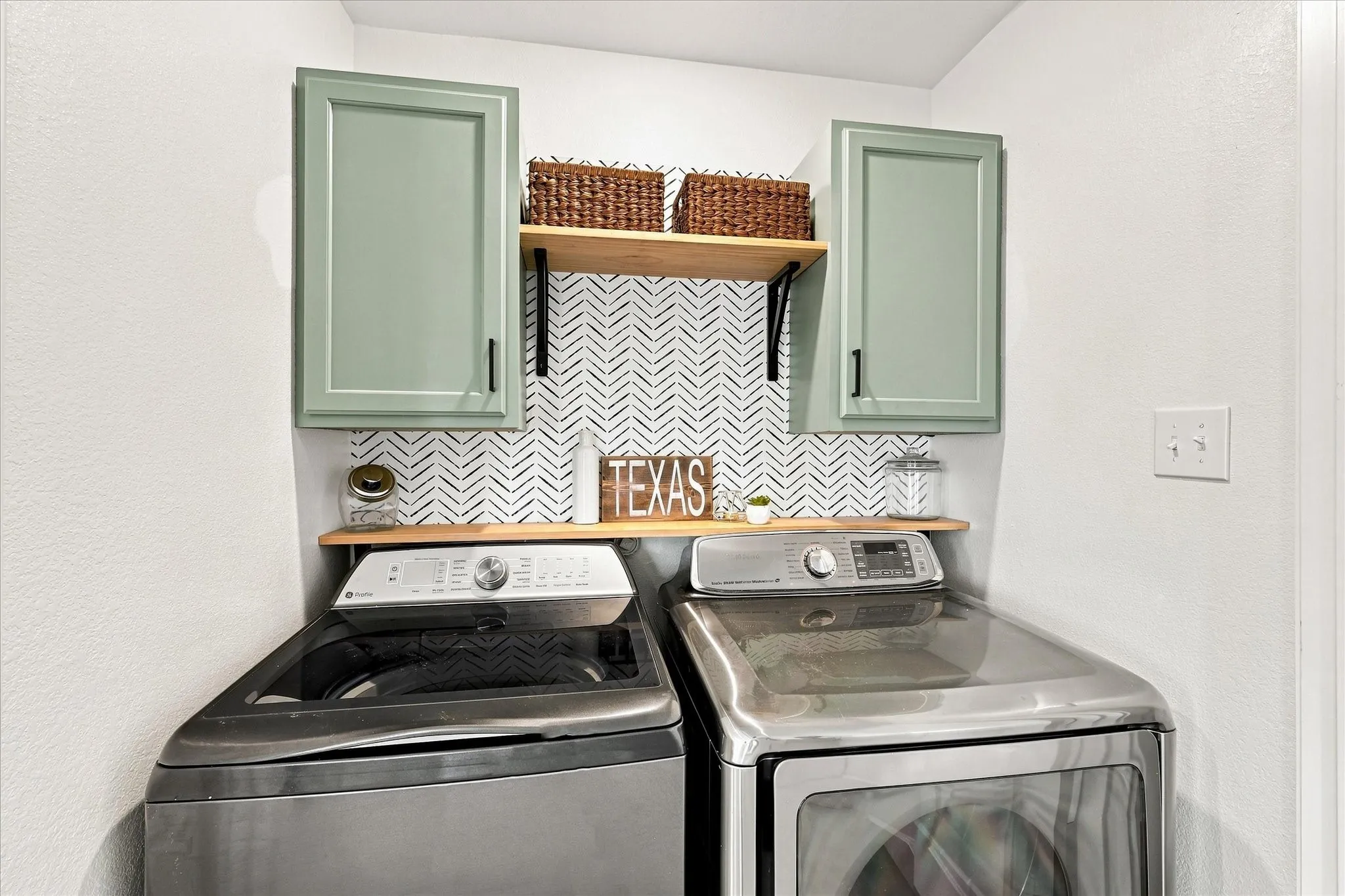 Custom cabinetry with matte black hardware, wood-finish shelving, and patterned wall covering