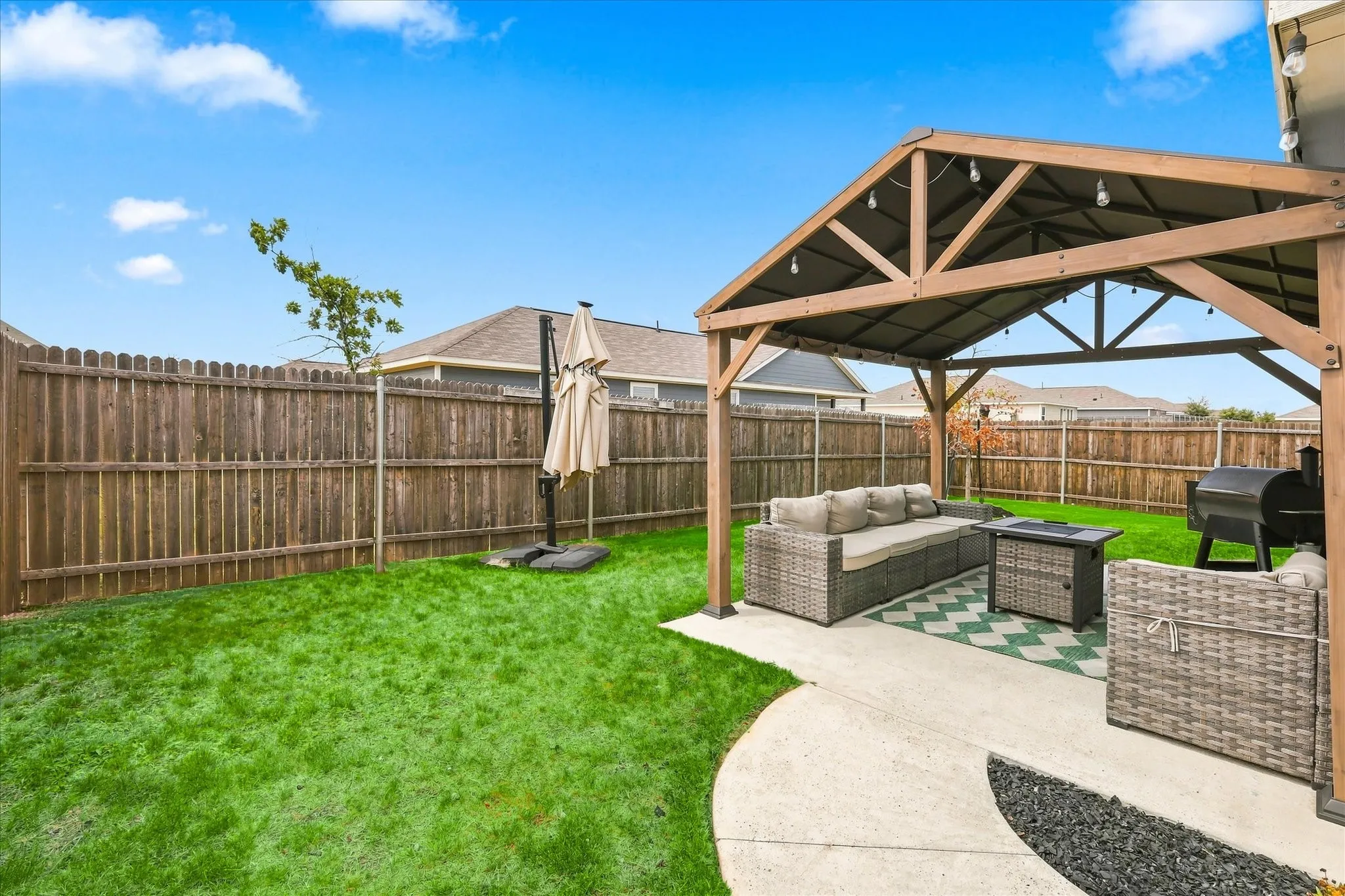 Expansive backyard featuring a wood privacy fence, a covered patio structure, and a concrete patio