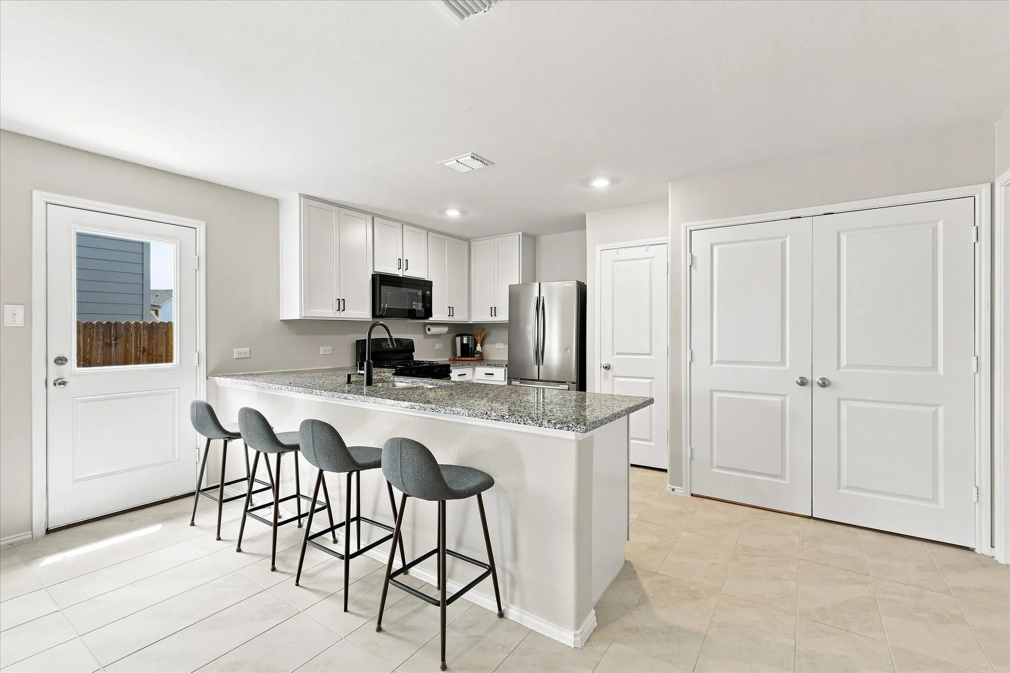 Kitchen featuring an island with stone-finish countertops, white cabinetry, and stainless steel appliances
