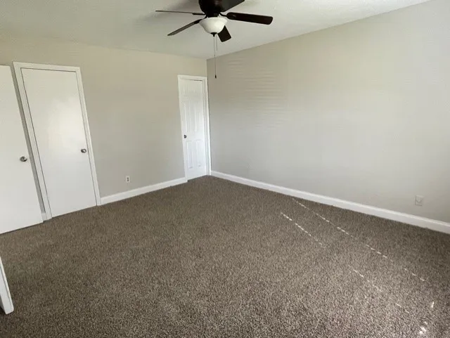 Plush carpeting, neutral wall tones, white trim, and a ceiling fan with integrated lighting